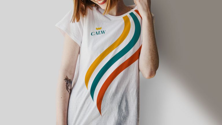 Frau mit weißem T-Shirt im Stadt Calw Design – wellenförmiges Branding in Orange, Gelb und Türkis